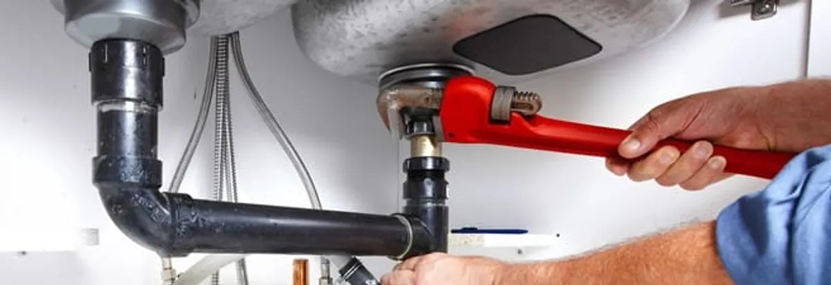 Garbage disposal repair technician tightening the sink drain and disposal connection in San Antonio, TX