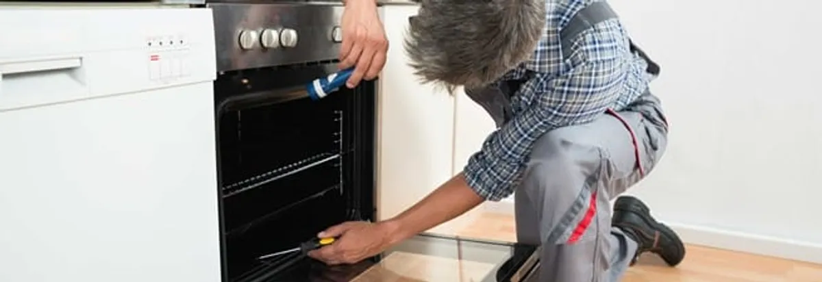 Oven repair technician inspecting and servicing an electric oven in San Antonio, TX