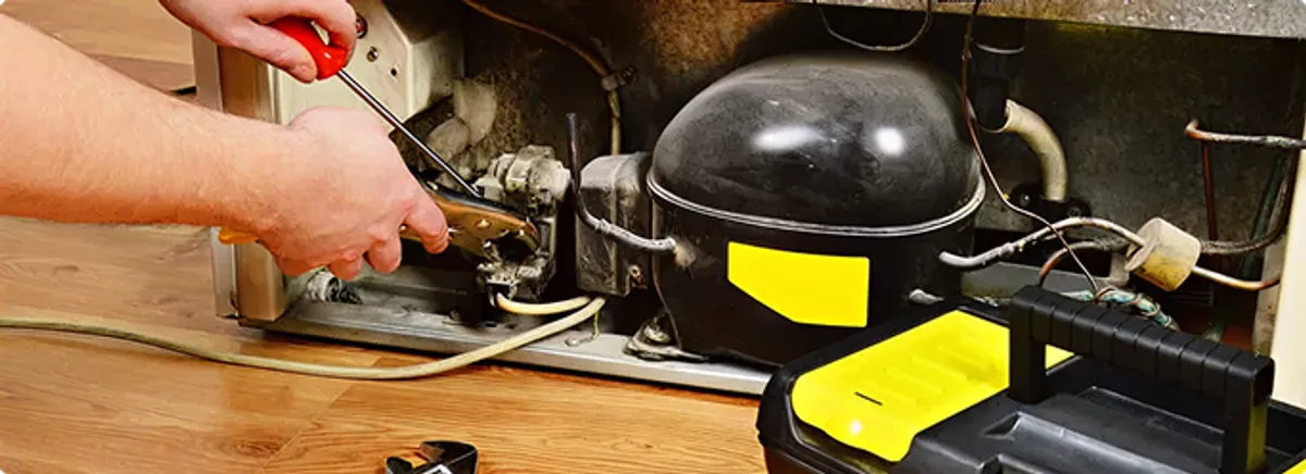 Refrigerator repair technician fixing the compressor and wiring in San Antonio, TX